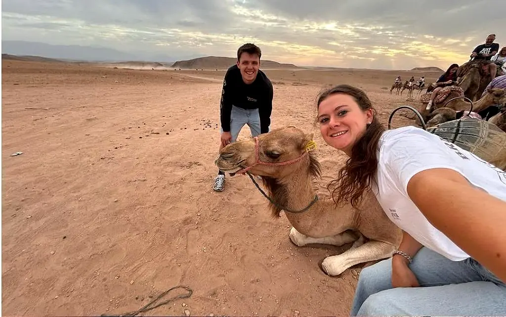 Guests walking with camels across the Agafay landscape